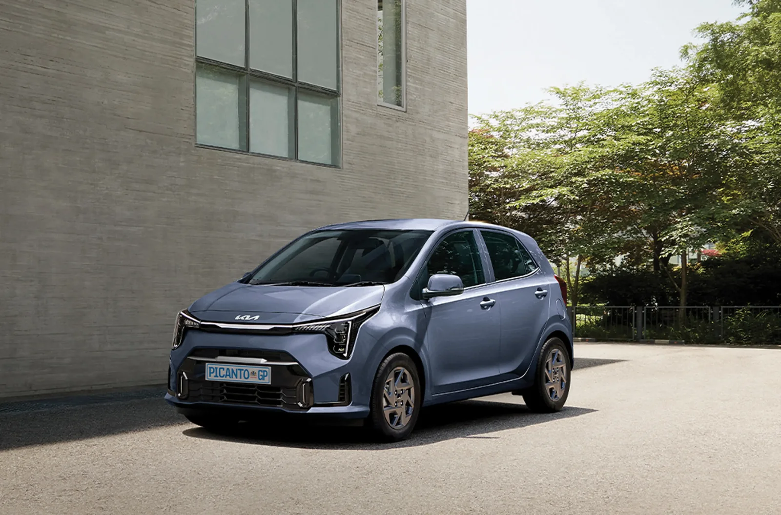 Grey-blue Kia Picanto parked outside a modern building